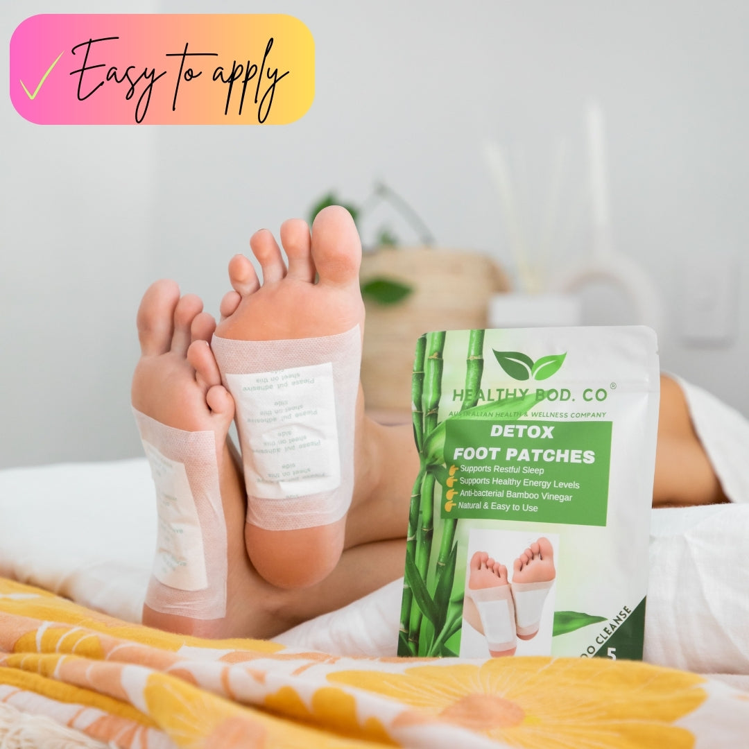 An image of a woman wearing detox foot patches while she lays on the bed.